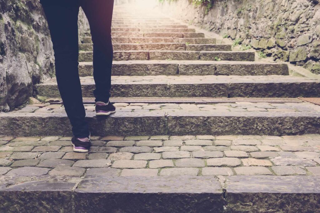 Woman walking up some outdoor stone stairs,  background with vintage filter.